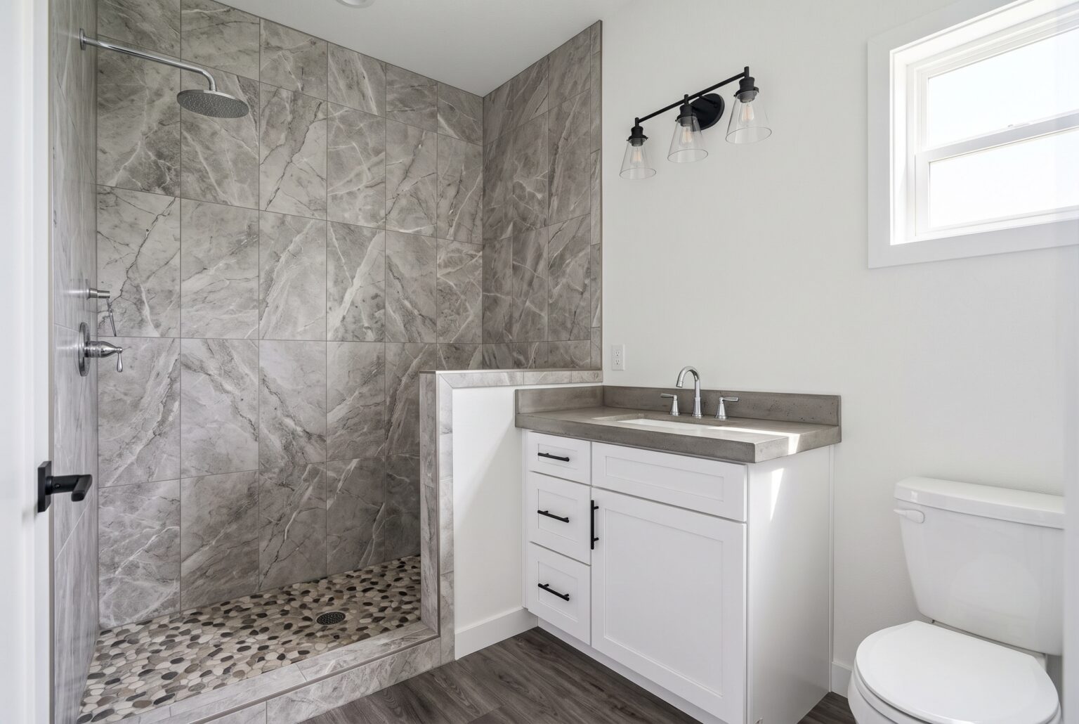 Finished bathroom with a walk-in marble look tile shower, white vanity and concrete look counter